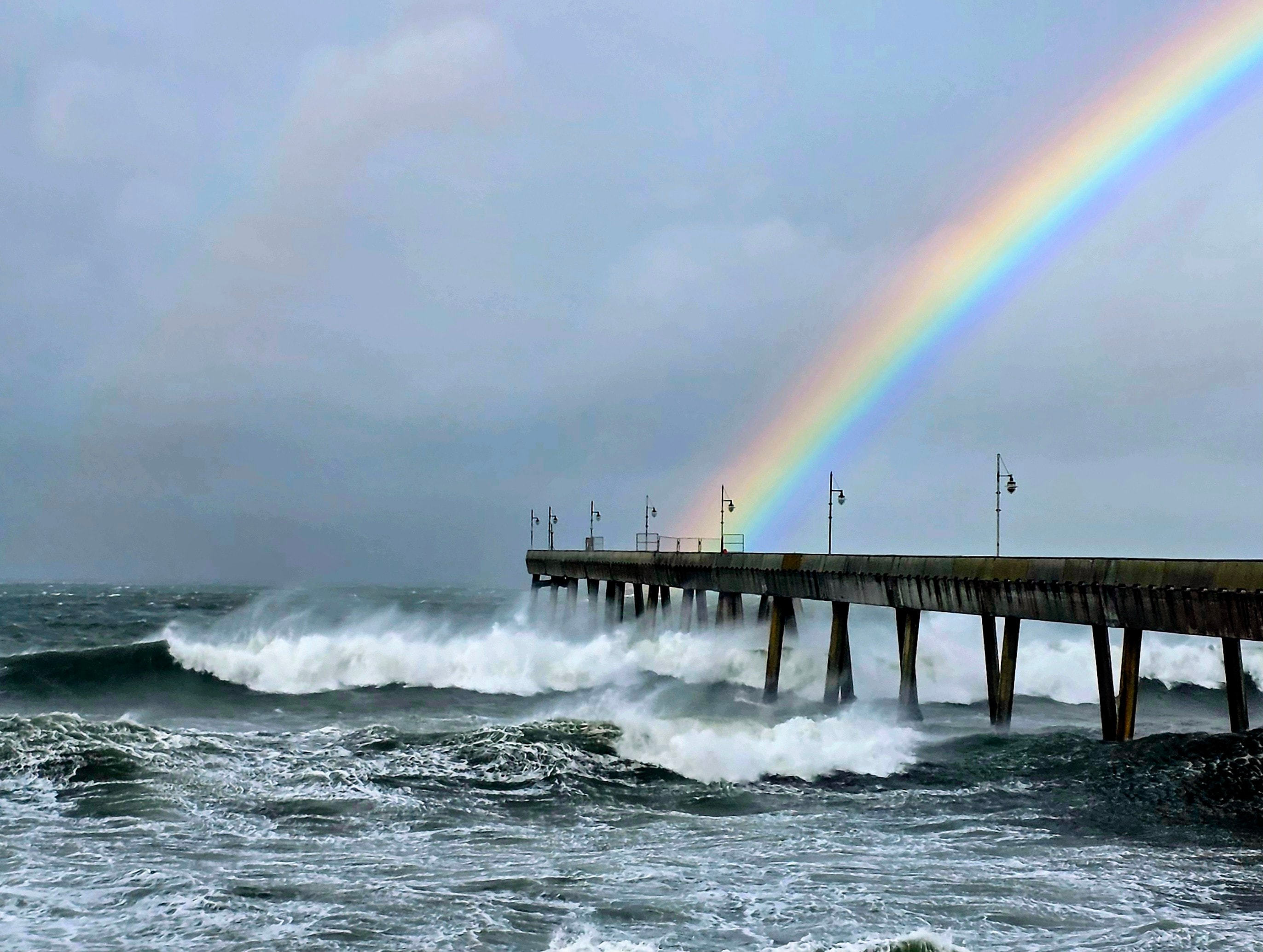 Storm swell breaking at the Pacifica Pier under a dramatic sky